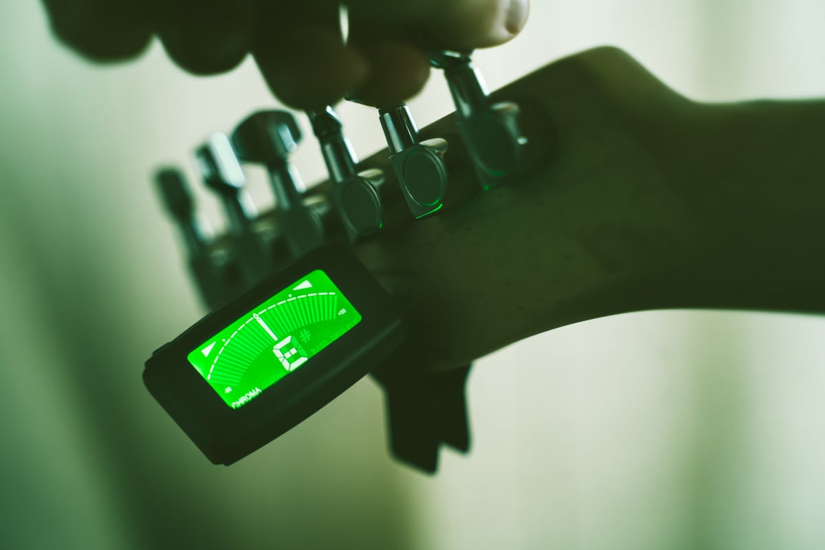 Tuning Electric Guitar With Chromatic Tuner. Shallow Depth Of Field